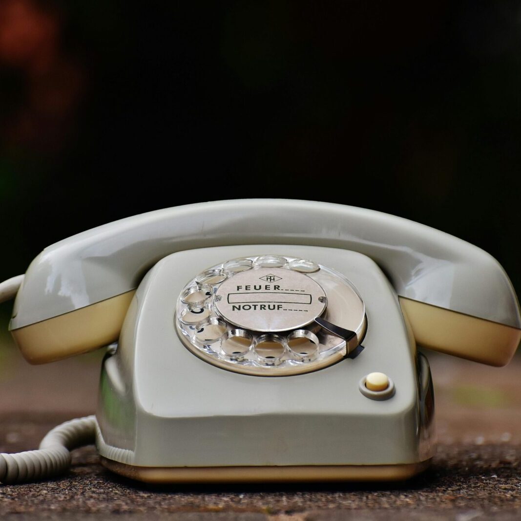 Close-up of a vintage rotary dial telephone with a nostalgic design on a wooden surface.